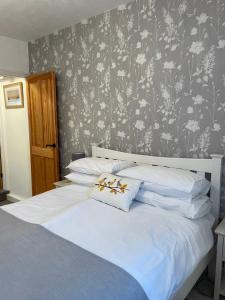 a bedroom with a white bed with a floral wallpaper at Trout Cottage in Filey