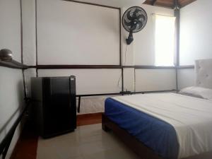 1 dormitorio con 1 cama y reloj en la pared en HOSPEDAJE VILLA CAMPESTRE "ALONDRA" Parqueo Privado GRATIS! en Villavicencio