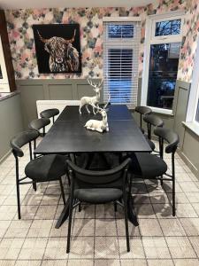 a dining room table with chairs and a statue of a deer on it at Luxury Lodge With Hot Tub In Royal Deeside in Strachan