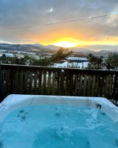 a hot tub on a deck with a sunset in the background at Luxury Lodge With Hot Tub In Royal Deeside in Strachan