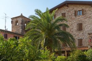 uma palmeira em frente a um edifício em Hotel Antico Monastero em Toscolano Maderno