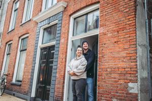een man en vrouw die in een raam van een bakstenen gebouw staan bij B&B Holm in Groningen