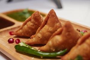 a plate of dumplings with a green pepper on a table at Hotel Santeria Inn, Best Luxurious Hotel AC Rooms In Surat in Surat