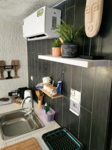 a small kitchen with a sink and a microwave at Escapade dans un jardin avec piscine in Lomé