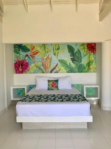 1 dormitorio con 1 cama con una pintura en la pared en Casa de las Flores tropical, en San Andrés