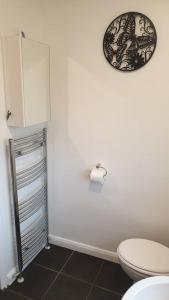 uma casa de banho com WC e um relógio na parede em Entire house in Sherwood, Nottingham em Nottingham