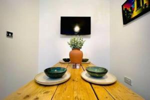 two bowls on a wooden table with a vase at Cosy - Stylish - Close to Centre in Cardiff