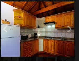 kuchnia z drewnianymi szafkami i białą lodówką w obiekcie Casa las toscas w mieście Calera