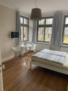 Un dormitorio con una cama, un escritorio y ventanas. en Alte Häuslerei, en Boltenhagen