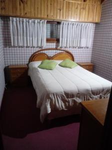 a bedroom with a large bed with two green pillows at Triplex a dos cuadras del mar in Necochea