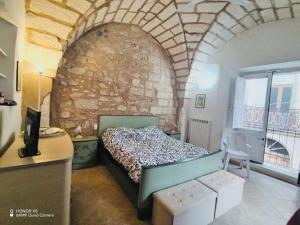 1 dormitorio con cama y pared de piedra en La casa del pellegrino, en Carpignano Salentino