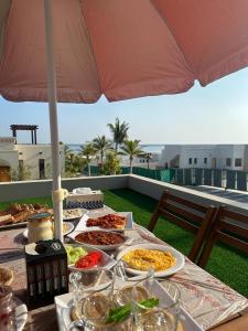 stół z talerzami jedzenia i parasolką w obiekcie Sifah Ocean Breeze Villa w Maskacie