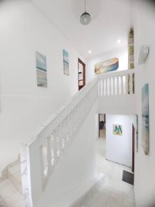 a white staircase in a home with paintings on the walls at Villa KELIA Biyem-Assi Acacias in Yaoundé