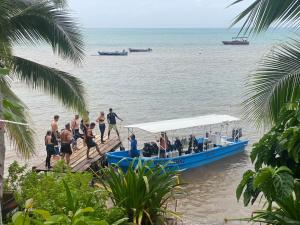 un grupo de personas en un barco azul en la playa en Las Palmeras OceanView Hotel and Dive Center, en Little Corn Island