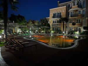 Una piscina frente a un edificio por la noche. en MARINA Apartments, en Ravda