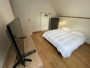 a bedroom with a white bed and a television at Chambre meublé idéale pour déplacement d'affaires in Le Petit-Quevilly