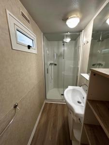 a bathroom with a shower and a white sink at Kamp Slanik Mobile Homes in Umag
