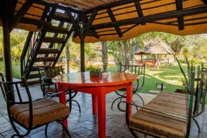 a red table and chairs on a patio at Lion's Den Guesthouse Otjiwarongo in Otjiwarongo
