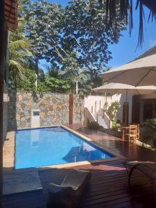 - une piscine avec une table et un parasol dans l'établissement Pousada Manguezal, à Icaraí