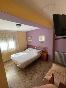 a bedroom with a bed and a flat screen tv at Hostal Casa Martina in Guadalaviar