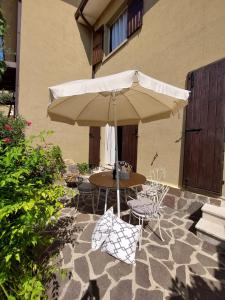 a table and chairs under an umbrella on a patio at Casa Malina Ferienhaus im Grünen am Gardasee in Toscolano Maderno