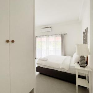 a white bedroom with a bed and a window at Isara Khao Lak in Khao Lak