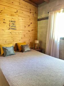 a bedroom with a bed with a wooden wall at Cabañas del Amanecer in Tanti