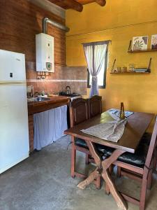 a kitchen with a wooden table and a white refrigerator at Cabañas del Amanecer in Tanti