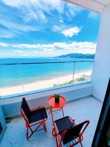 einen Balkon mit 2 Stühlen, einem Tisch und dem Strand in der Unterkunft CĂN HỘ TMS LUXURY RESIDENCES 28 NGUYỄN HUỆ QUY NHƠN in Quy Nhon