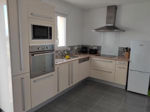 una cocina con armarios blancos y electrodomésticos de acero inoxidable en Maison à la campagne en Villiers-sur-Tholon