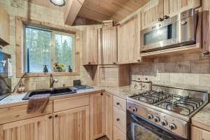 a kitchen with wooden cabinets and a stove top oven at Barnum Cabin on 30 Acres with Soo Line Trail Access! 