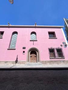 un edificio rosa con una puerta y ventanas marrones en Casa Maka en San Luis Potosí