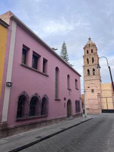 a pink building and a church with a tower at Casa Maka in San Luis Potosí