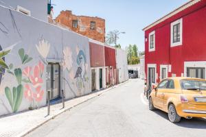 un coche naranja estacionado en una calle con un mural en Alcantara Charm 3BR Apartments, en Lisboa
