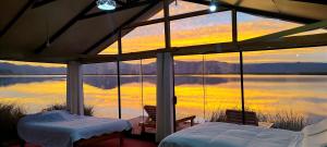 a room with a view of a lake with two beds at Titicaca Halso Los uros in Puno