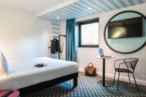 - une chambre avec un lit, un miroir et une chaise dans l'établissement ibis Styles Paris Saint Denis Pleyel, à Saint-Denis