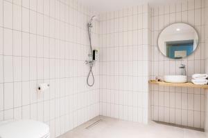 a white tiled bathroom with a shower and a sink at ibis Styles Paris Saint Denis Pleyel in Saint-Denis