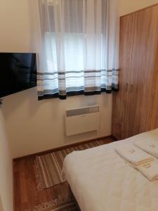 Habitación pequeña con cama y ventana en Milnik apartman, en Zlatibor
