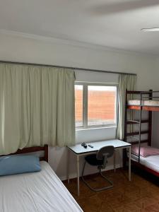 a bedroom with a desk and a bed and bunk beds at Hotel Pousada Liberdade in Pindamonhangaba