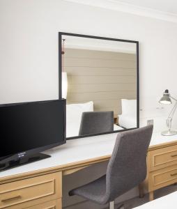 a desk with a computer monitor and a mirror at Holiday Inn Peterborough West, an IHG Hotel in Peterborough
