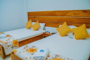 Duas camas num quarto com almofadas amarelas em Hotel Cielo Tarapoto em Tarapoto