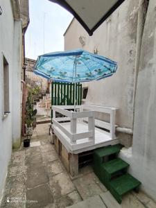 eine Bank mit einem blauen Regenschirm und ein paar Treppen in der Unterkunft La casa del pellegrino in Carpignano Salentino