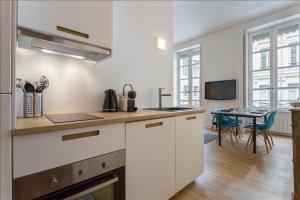 een keuken met witte kasten en een eetkamer met een tafel bij Patchwork - Location meublé T2 - Lyon 2 in Lyon