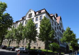 Modernes Zwei-Zimmer-Apartment Chemnitz - Kaßberg في شيمنيتز: مبنى ابيض كبير فيه سيارات تقف امامه