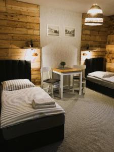 a bedroom with two beds and a table and chairs at Gościniec Rajec in Rajcza