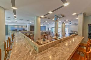 a large lobby with a bar and tables and chairs at Rede Andrade Vela Branca in Recife