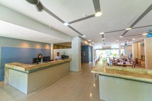 a lobby with two people sitting at a counter at Rede Andrade Vela Branca in Recife