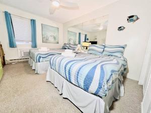 Stunning 2BR/2BA Bayfront Retreat في آوشين سيتي: سريرين في غرفة نوم مع ملاءات زرقاء وبيضاء