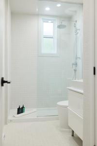 a white bathroom with a shower and a toilet at New and Cozy 3 bedroom in Le Plateau by Denstays in Montreal
