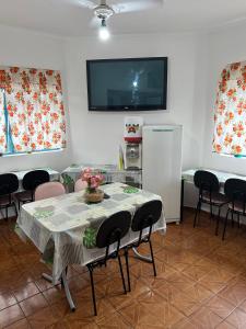 a dining room with a table and chairs and a tv at Hotel Pousada Liberdade in Pindamonhangaba